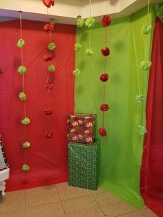 a room decorated with red and green paper pom poms hanging from the ceiling