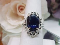 "Simulated Blue Sapphire Ring Vampire Design#84 MADE TO ORDER Inspired by Gothic & Renaissance era jewelry, I now offer this lovely Antique styles ring in sterling silver. This gorgeous ring is set with a flawless simulated sapphire gemstone. This stunning gemstone has excellent color and clarity. The oval full cut 7ct oval sapphire is 14mm (9/16th of an inch) Long by 10mm Wide (3/8th\"). The ring sits 8mm off the finger. The inside of the band is marked 925 for sterling. Notice the intricat Oval Blue Sapphire Ring Stamped 925, Elegant Oval Sapphire Ring Stamped 925, Oval Sapphire Ring With Vs Clarity For Gift, Oval Sapphire Ring With Vs Clarity As Gift, Gothic Filigree, Vampire Design, Antique Style Rings, Gothic Ring, Order Design