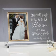 a clear acrylic photo frame with a gold ribbon on the table next to it