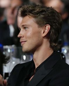 a close up of a person in a suit and tie at a table with other people