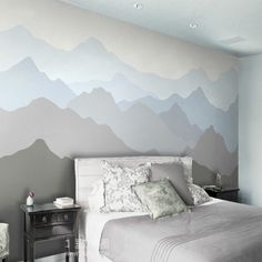 a bedroom with mountains painted on the wall and two nightstands in front of it