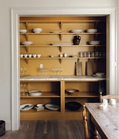 the shelves in this kitchen are filled with dishes and cups, along with empty plates