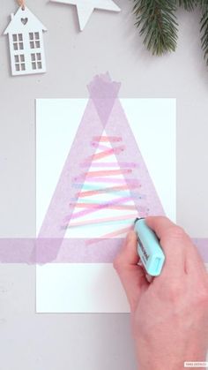 someone is making a christmas tree card out of construction paper and colored crayons