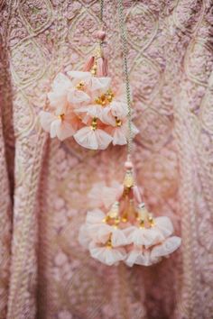 three pink flowers hanging from the side of a woman's dress with gold beads