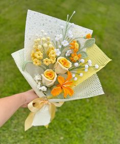 a hand holding a bouquet of flowers on top of a green grass covered park area