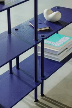 a blue shelf with books and a white vase on top