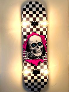 a skateboard with a skull and pink ribbon on it's side hanging from the wall