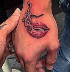 a person with a tattoo on their hand holding an octopus in front of his face