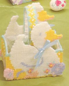 two little baskets with ducks in them on a green tablecloth next to an easter egg