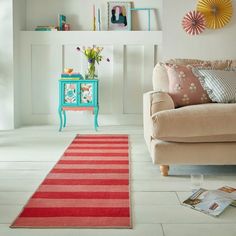 a living room with a red and white rug on the floor next to a couch