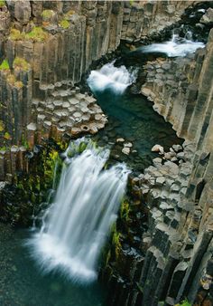 an aerial view of a waterfall in the middle of some rocks with water running down it