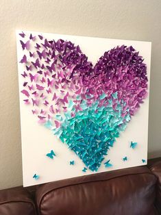 a heart made out of purple and blue butterflies on a white canvas with brown leather couch