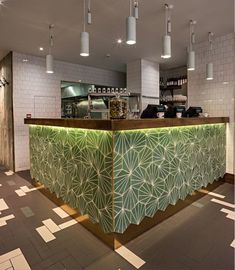 the interior of a restaurant with green and white tiles on the floor, along with lights hanging from the ceiling