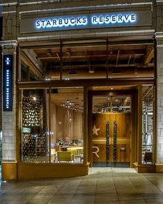 the entrance to starbucks reserve is lit up at night