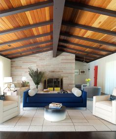 a living room filled with furniture and a fire place under a wooden ceiling covered in wood planks