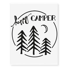 a black and white logo with the words happy camper in front of some trees