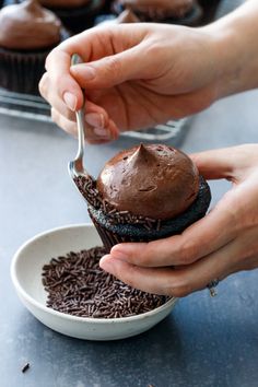 a person scooping chocolate from a cupcake in a bowl