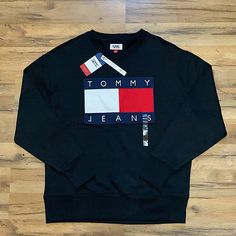 Brand New Tommy Hilfiger Logo Print Sweatshirt For Fall, Tommy Hilfiger Black Crew Neck Top, Tommy Hilfiger Sporty Black Tops, Tommy Hilfiger Black Long Sleeve Top, Tommy Hilfiger Black Tops For Fall, Black Tommy Hilfiger Tops For Fall, Tommy Hilfiger Long Sleeve Streetwear Tops, Tommy Hilfiger Sweatshirt Mens, Tommy Jeans Hoodie