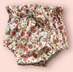 the bottom of a diaper with red flowers on it, against a pink background