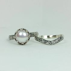 two silver rings with white pearls on them