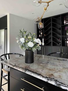 a marble counter top in a kitchen with black cabinets and bar stools next to it