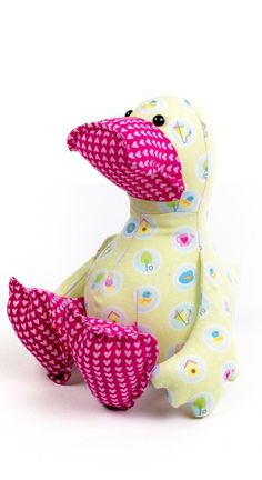 a yellow ducky stuffed animal sitting on top of a white surface with pink and blue polka dots