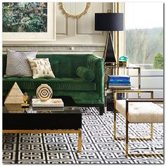 a living room with green velvet couches and black tables in front of a large window