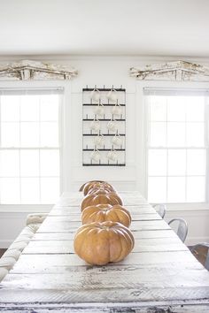 a table with pumpkins sitting on top of it in front of two large windows