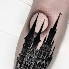 a black and white photo of a castle tattoo on the leg