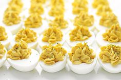 an assortment of deviled eggs are arranged on a white surface with herbs sprinkled on them