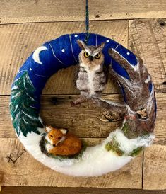 an ornament is hanging on a wooden wall with two animals and a squirrel