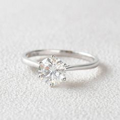 a white gold ring with a round brilliant cut diamond set in the shants on top