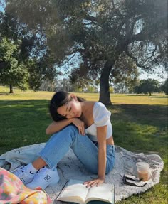 a woman sitting on top of a blanket next to a tree