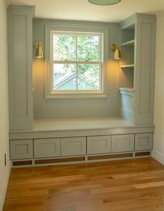 an empty room with built - in shelves and a window above the bench is shown