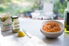 a bowl of food next to a bottle of mayonnaise and a spoon on a table