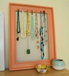 an orange frame holds several necklaces and a bowl on a table next to it