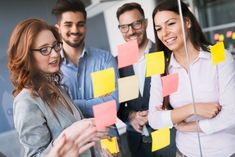 group of people standing around each other with sticky notes on them