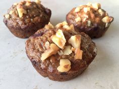 three muffins with nuts and cheese on top sitting on a white countertop