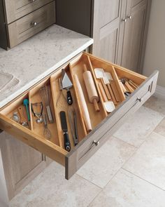 an open drawer in the middle of a kitchen with utensils and spoons