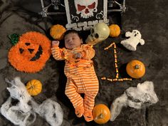 a baby is laying on the floor surrounded by halloween decorations