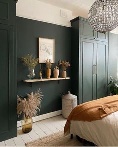 a bedroom with green painted walls and white flooring, plants in vases on the shelf