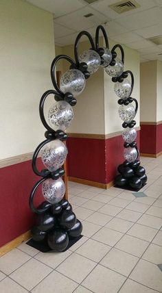 an arch made out of black and silver balls in the middle of a tiled floor