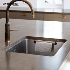 a stainless steel sink and faucet in a kitchen with marble countertops, cabinets and drawers