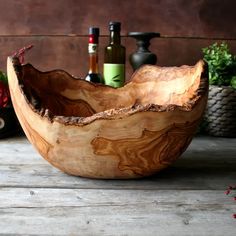 a wooden bowl sitting on top of a table next to bottles and flowers in vases