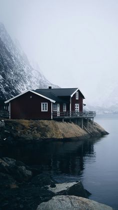 a red house sitting on top of a rocky shore