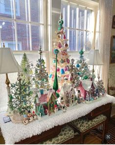 a christmas tree is sitting on a table in front of a window with two lamps