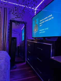 a bedroom with purple lighting and a flat screen tv on the wall, next to a dresser