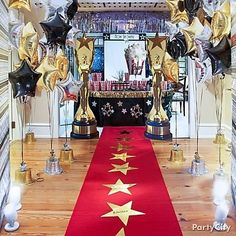 a red carpet with gold stars on it and balloons in the shape of golden stars