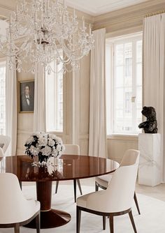 an elegant dining room with chandelier and white chairs