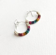 This handwoven earring features a herringbone pattern and bold rainbow colors.  Bead by bead, each earring is crafted by hand and woven together in colorful whimsy.  Earring handwoven tube is affixed to a 14k gold filled hoop or sterling silver hoop and all beads are made of glass. Because of the handmade nature of this item, slight variations in color and size can occur. Listing is for 1 single pair of earrings.  Shown in sterling silver option. Multicolor Beaded Earrings For Everyday, Everyday Multicolor Earrings With Tiny Beads, Adjustable Multicolor Woven Beaded Earrings, Multicolor Woven Adjustable Beaded Earrings, Adjustable Rainbow Earrings With Tiny Beads, Multicolor Woven Jewelry With Round Beads, Multicolor Woven Beaded Dangle Earrings, Handwoven Rainbow Jewelry For Gifts, Handwoven Rainbow Jewelry Gift